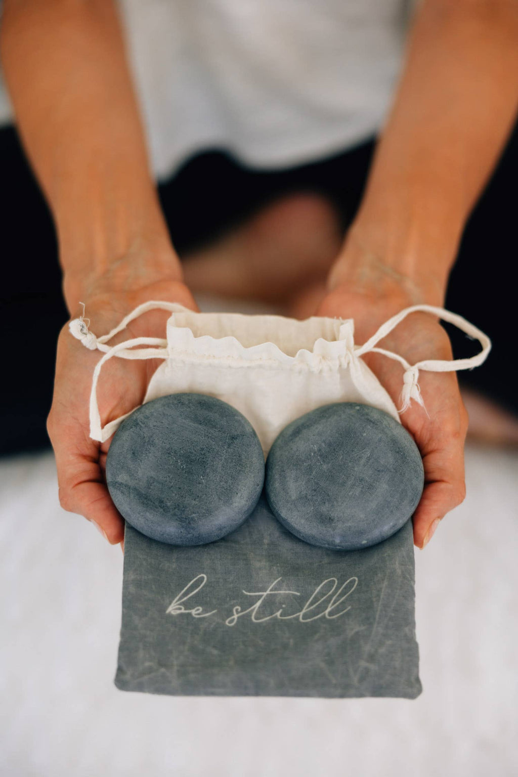 Pair of smooth grey palewa stones resting on a cotton drawstring bag