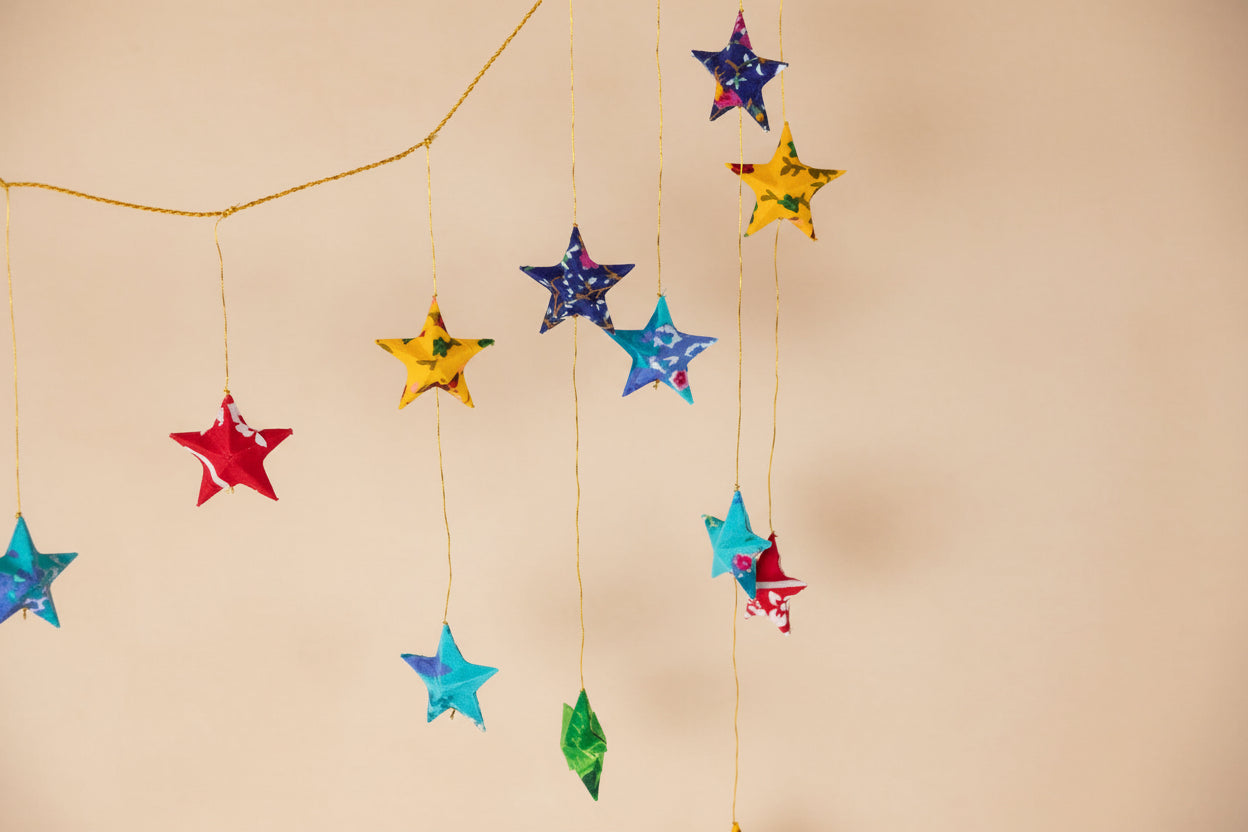 Colorful star-shaped decorations hanging on a string against a white background