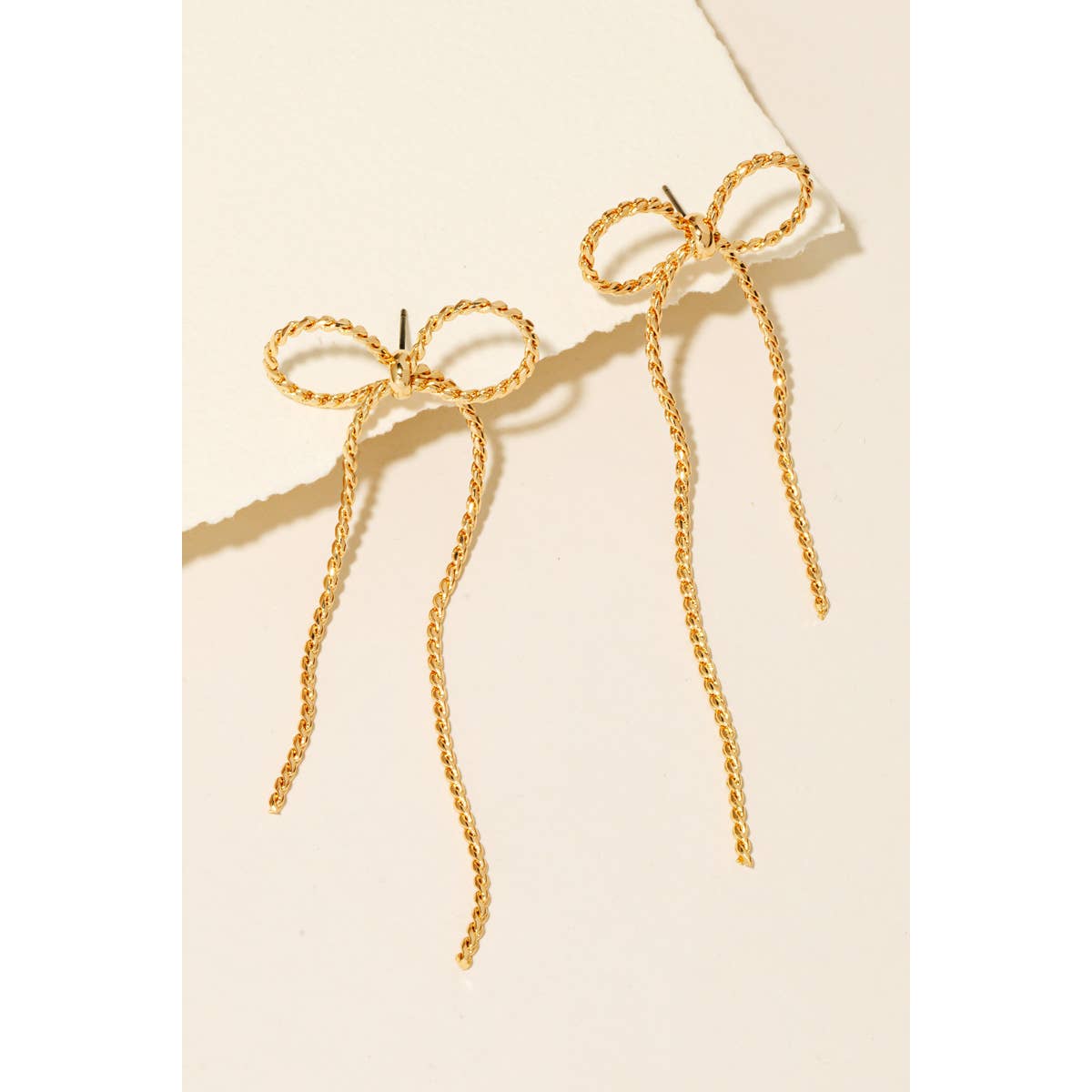 Gold rope chain and ribbon bow dangle stud earrings displayed on card