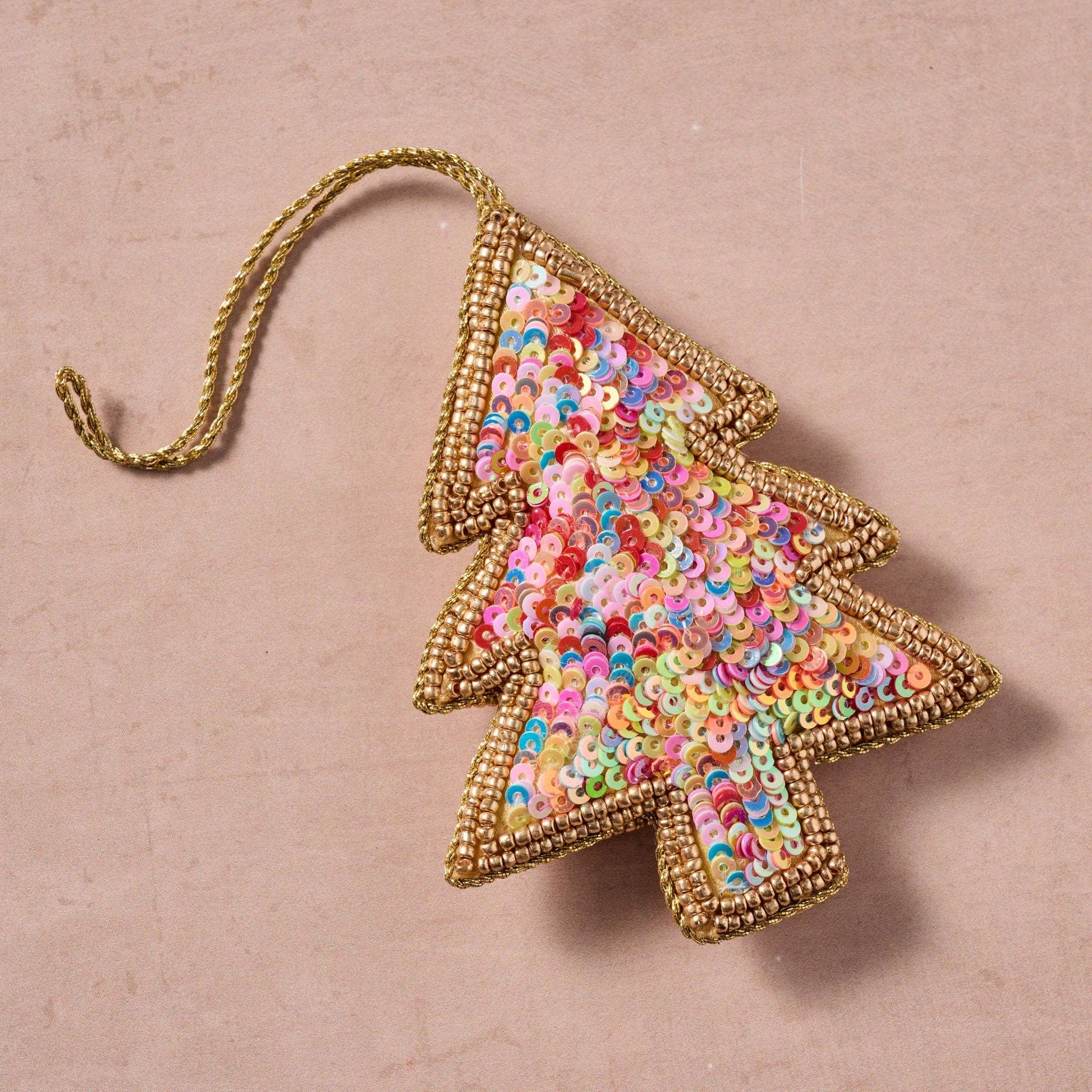 Decorative Christmas tree ornament with colorful sequins on a natural stone countertop