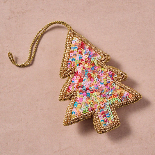 Decorative Christmas tree ornament with colorful sequins on a natural stone countertop