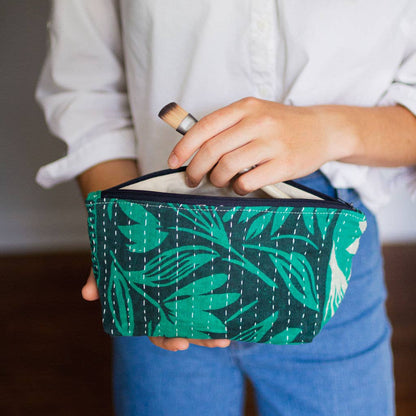 Person holding a green patterned pouch with a white interior.