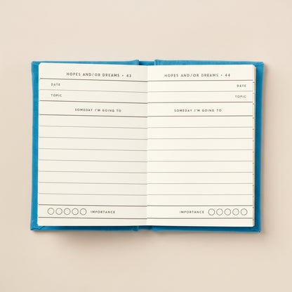 Open mini journal with blue hardcover on a beige background