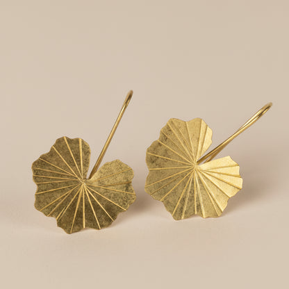 Pair of brass lotus leaf-shaped earrings on a light gray background