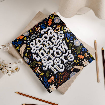 Notebook with decorative cover on a white surface with pencils and flowers