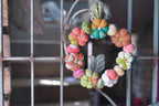 Decorative wreath with colorful flowers on a metal grid background