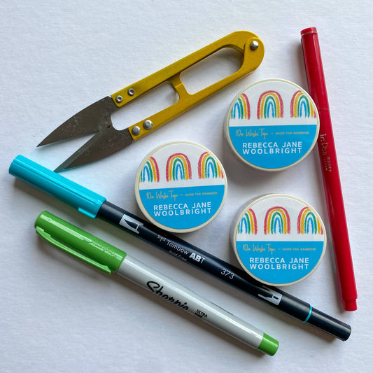 Roll of Over the Rainbow Washi Tape with label, next to scissors and stationery supplies
