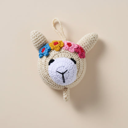 Crocheted llama toy with colorful flowers on a gray surface