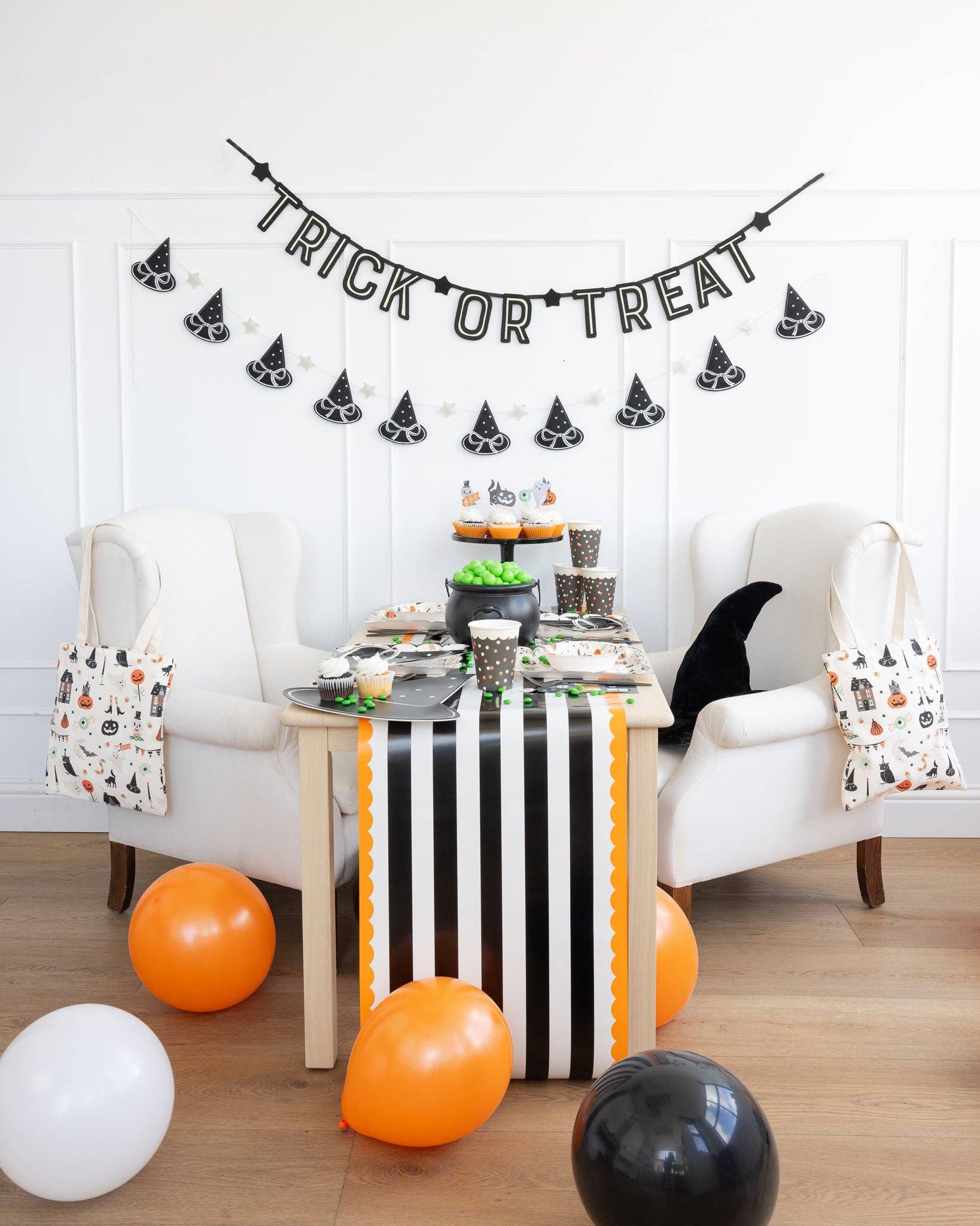 Puffy felt witch hats banner styled across a mantle with Halloween accents