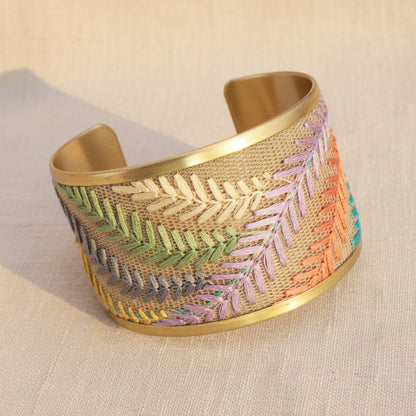 Decorative bracelet from Rochambeau Home with embroidered patterns on a textured surface with a neutral background