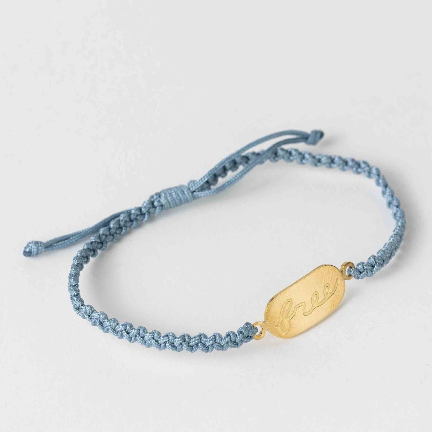 Blue braided bracelet with a gold tag on a light gray background