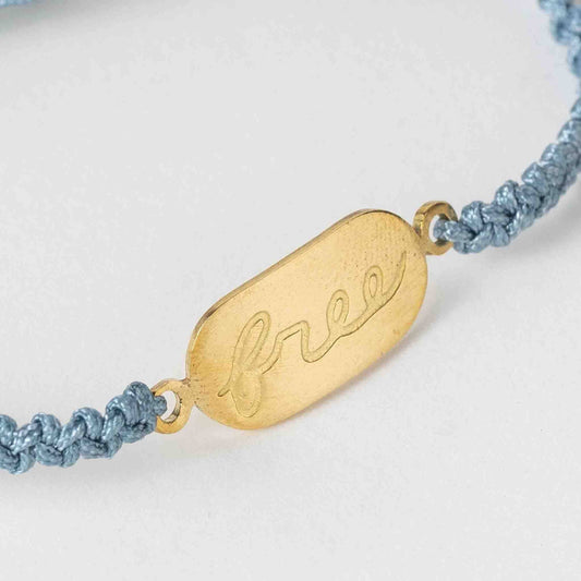 Bracelet with gold tag and blue cord on a white background