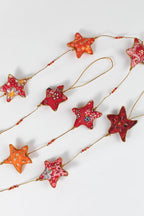A side view of the cotton fabric stars in warm red, yellow, and orange tones with gold beading