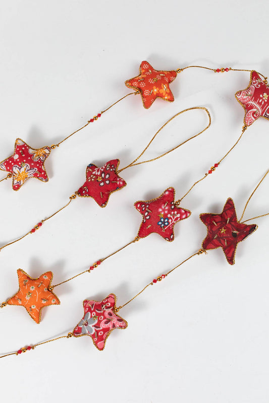 A side view of the cotton fabric stars in warm red, yellow, and orange tones with gold beading