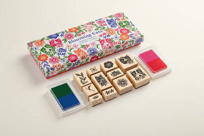 Set of wooden stamps with floral packaging and ink pads on a white background