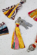 Colorful fabric keychains with tassels on a textured surface