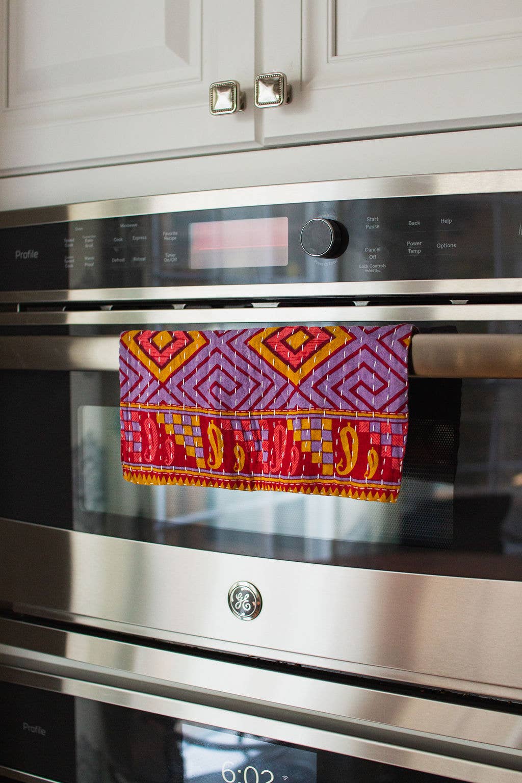 Stainless steel oven with a colorful towel draped over it in a kitchen setting