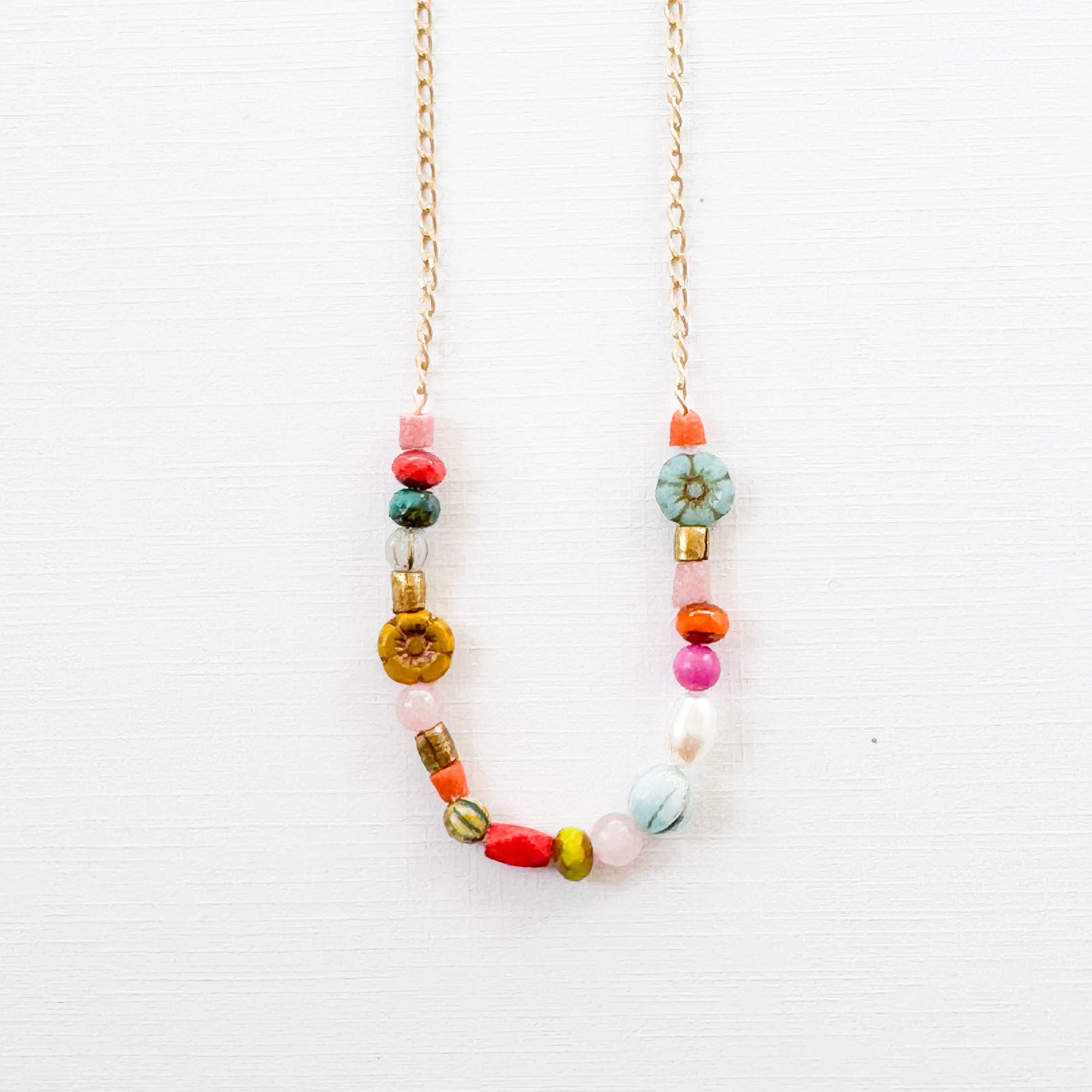 Flat lay of necklace components including pearls, Czech glass, and turquoise