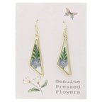 Close-up of gold diamond-shaped earrings with pressed blue flowers and ferns