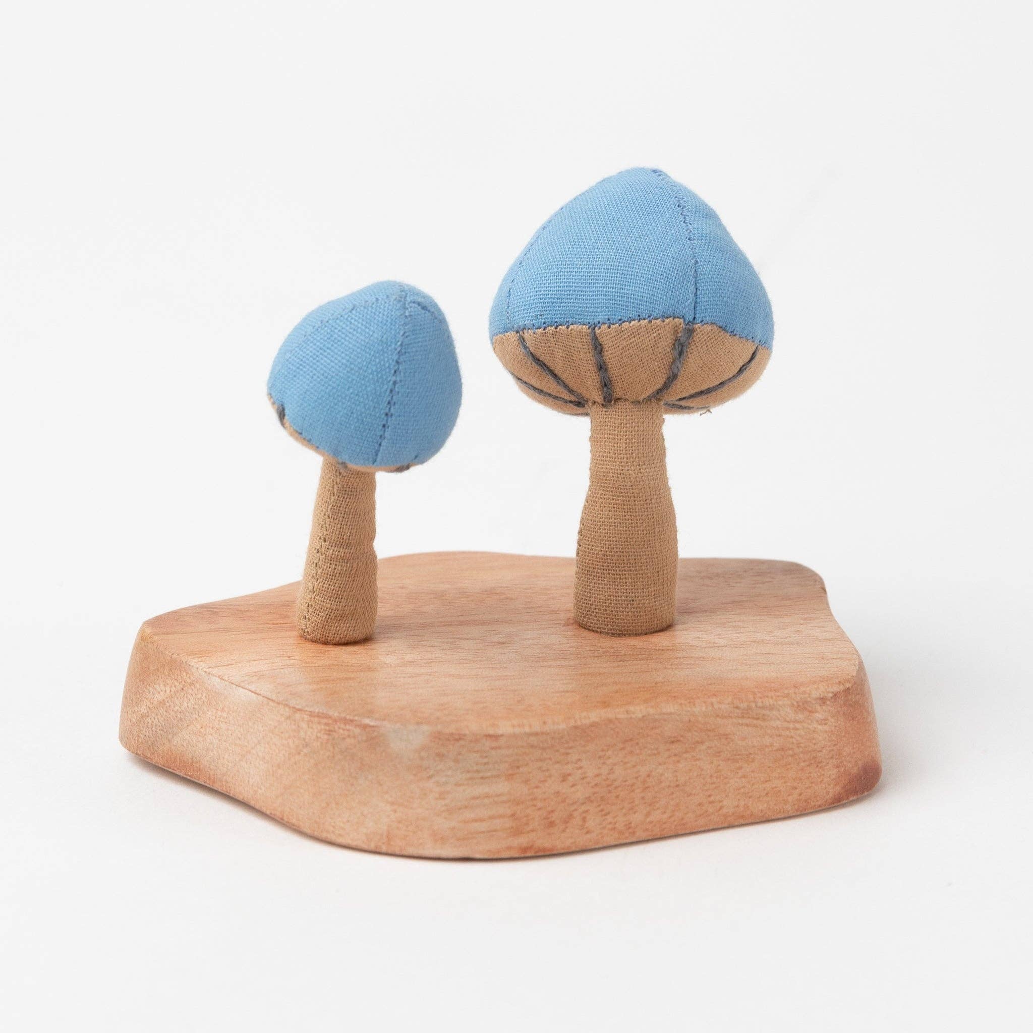 Two blue and beige fabric mushrooms sprouting from a rustic wooden base