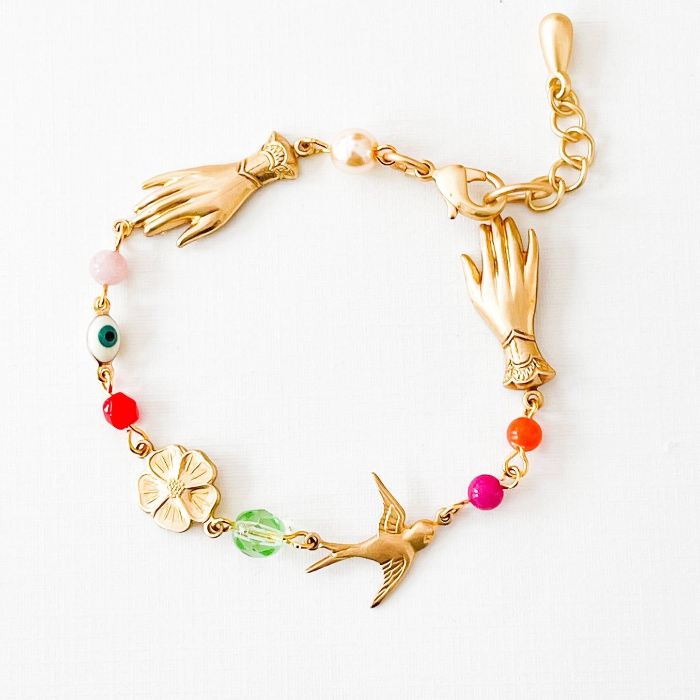 Handmade evil eye charm bracelet featuring pearl, coral, and colorful glass beads on white background