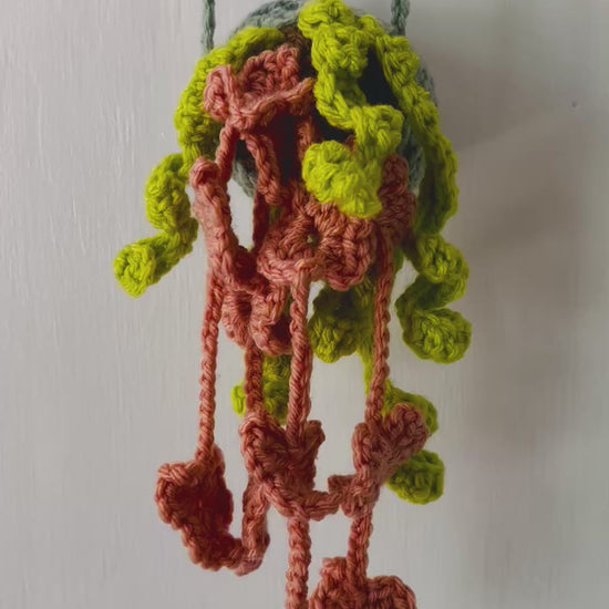 Crocheted botanical wall accent with delicate, dangling yarn hearts in swoon-worthy tones.