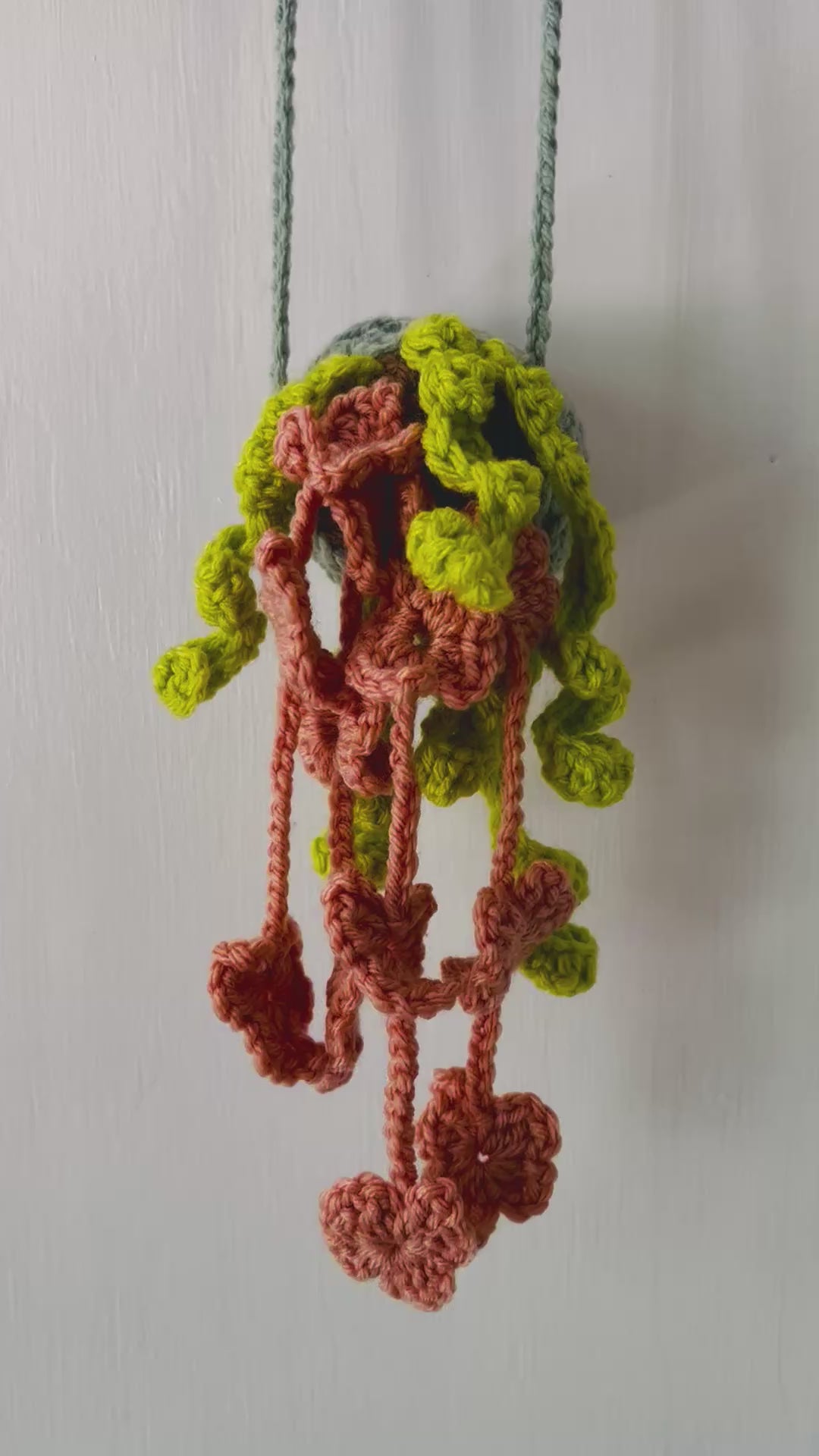 Crocheted botanical wall accent with delicate, dangling yarn hearts in swoon-worthy tones.